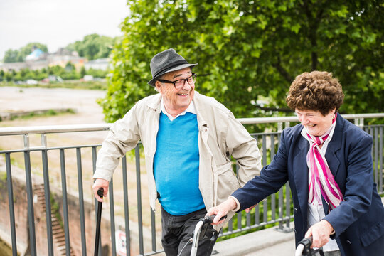 Laughing senior couple with walking stick and wheeled walker