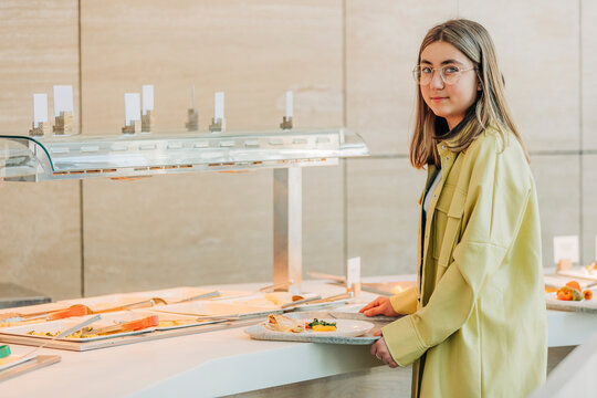 Teenage girl holding tray near buffet at school cafeteria