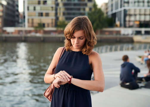 Germany, Hamburg, Young woman looking at watch
