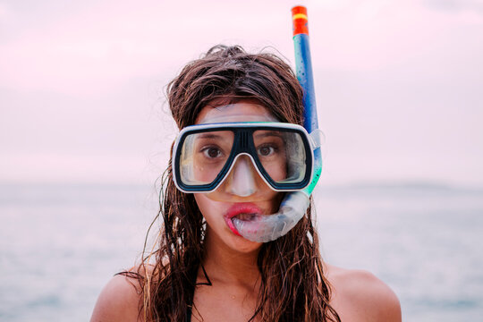 Young woman with diving goggles and snorkel pulling funny faces