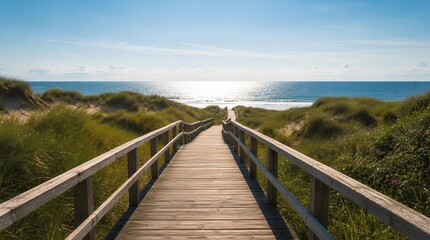 Obraz premium A wooden boardwalk leads through grassy sand dunes to a bright ocean beach under blue sky, suited for travel, tourism, vacation, and coastal lifestyle promotions.