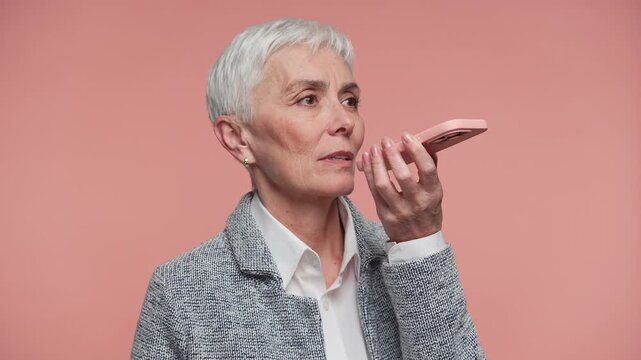 Senior Woman Using Smartphone Voice Assistant on Pink