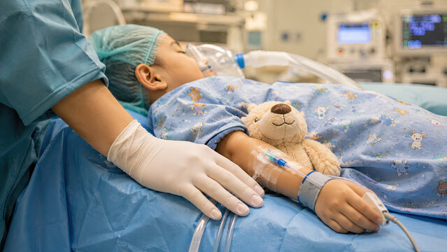 Pediatric anesthesiologist gloved hand gently resting near a child arm on an operating table. Gentle pediatric anesthesia care concept.