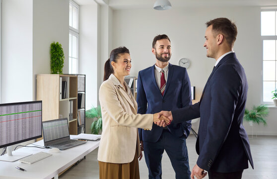 Business handshake in office confirms agreement. Team meeting aligns strategy to finalize partnership and drive success. Colleague watches, reinforcing teamwork. Deal done, clear win concept.