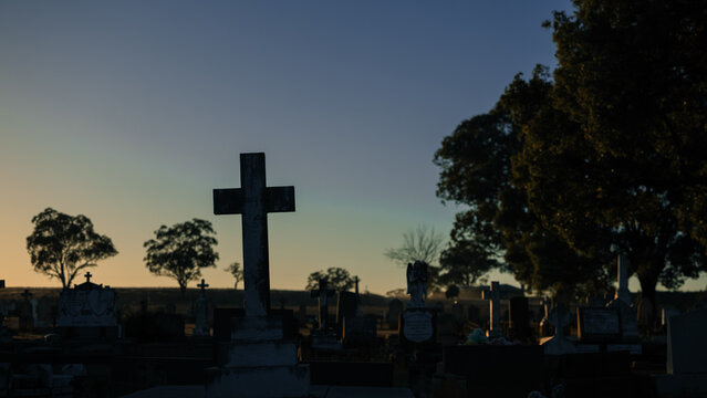 Serene cemetery at dawn with crosses and trees silhouetted against the sky