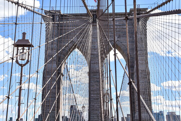 Fototapeta premium Suspension cables and granite towers of the iconic Brooklyn Bridge viewed from the pedestrian walkway on a bright sunny day in New York City, USA.