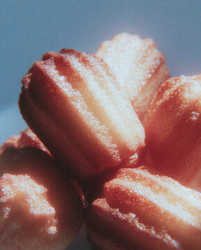 Nostalgic close-up of freshly baked madeleine cakes illuminated by warm, dramatic sunlight