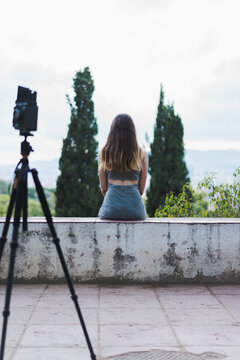 Spain, Barcelona, rear view of woman sitting on observation point at Montjuic with camera in foreground