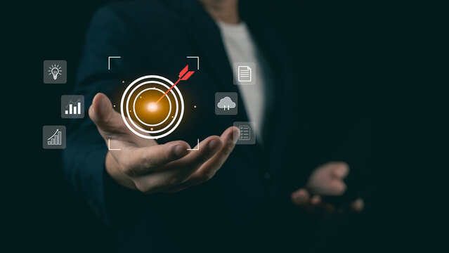 Businessman hand presenting glowing bullseye target with arrow icon, concept of business goal achievement and corporate strategy targeting.