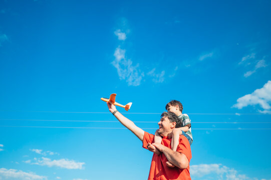 A father and son launch a toy airplane together outdoors