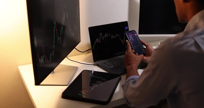Professional trader analyzes live financial charts across desktop, laptop, tablet, and smartphone in a modern office, monitoring market trends, tracking investments, and making trading decisions.