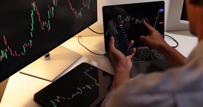Professional trader analyzes live financial charts across desktop, laptop, tablet, and smartphone in a modern office, monitoring market trends, tracking investments, and making trading decisions.