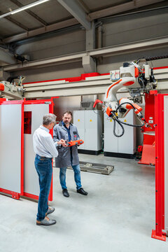Senior manager and engineer inspect an industrial robot indoors
