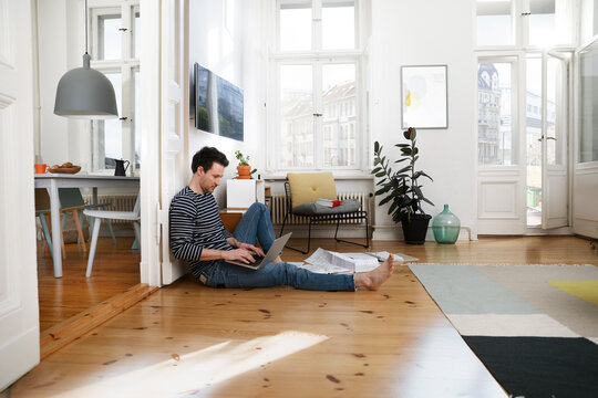 Man sitting in foor, using laptop, working from home