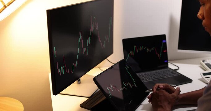 Professional trader analyzes live financial charts across desktop, laptop, tablet, and smartphone in a modern office, monitoring market trends, tracking investments, and making trading decisions.