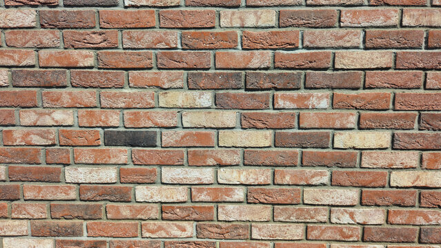 Weathered red brick wall with varied tones and visible mortar joints. Rustic masonry texture for architecture, construction and background design.