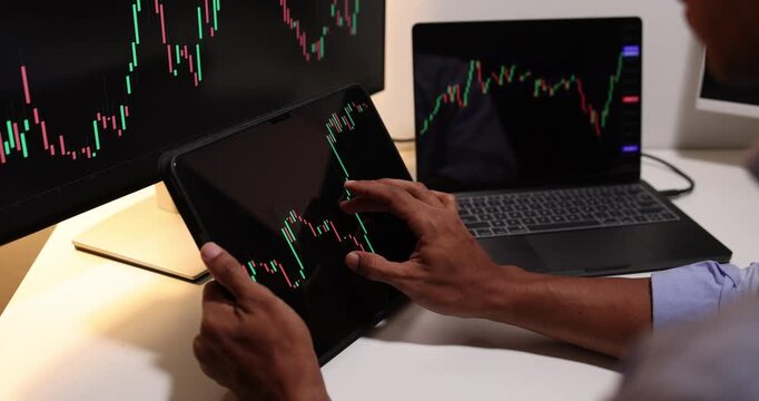 Professional trader analyzes live financial charts across desktop, laptop, tablet, and smartphone in a modern office, monitoring market trends, tracking investments, and making trading decisions.