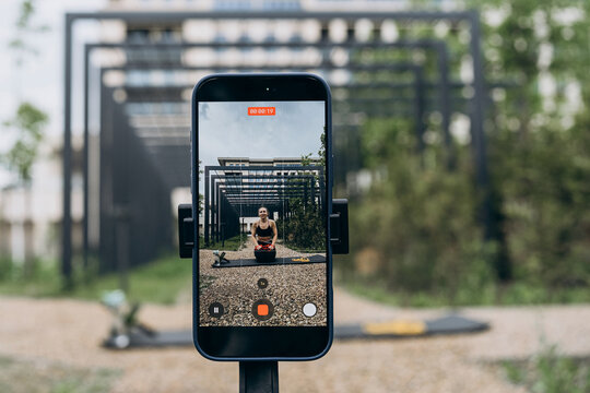 Smartphone records a woman filming a fitness tutorial outdoors