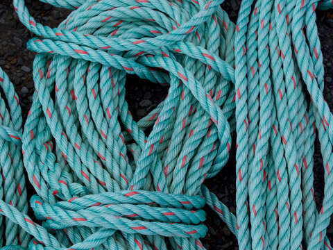 Turquoise fishing ropes have been coiled and stored creating an abstract pattern and image