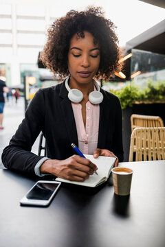 Portrait of businesswoman taking notes at pavement cafe