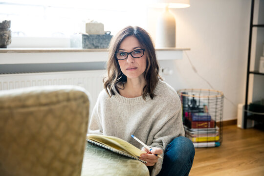 Woman sitting on floor, journalising in her diary