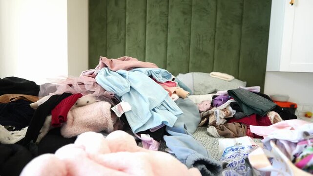 Messy clothes on bed in bedroom slow motion footage, pile of clothes on bed, person throwing clothes