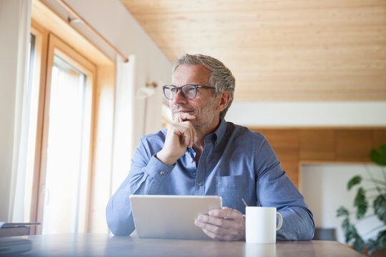 Mature man using digital tablet on table at home