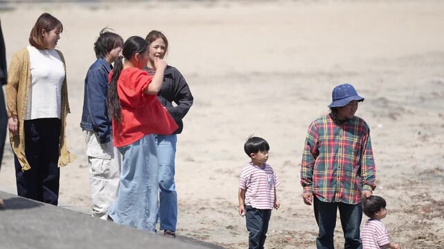 Group of people walks together on dry, sandy ground. Two adults hold children close, sharing a moment of calm. Man and young child walk side by side, quiet and thoughtful. Perfect for family, travel