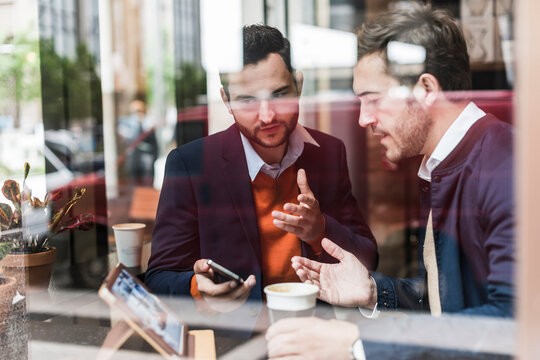 USA, New York City, Businessmen meeting in coffee shop, using mobile devices