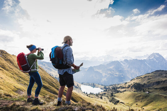 Germany, Bavaria, Oberstdorf, two hikers with map and binoculars in alpine scenery