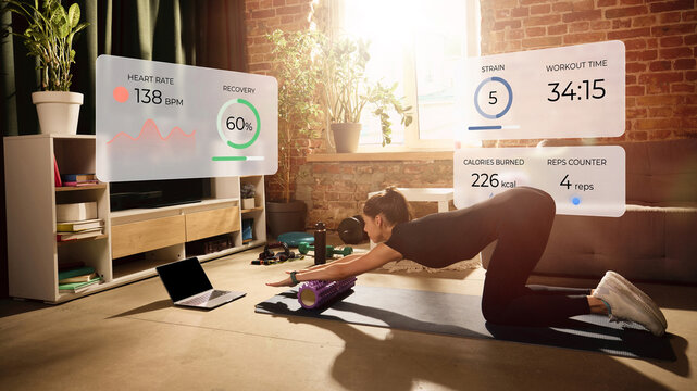 Woman using foam roller with smart recovery analytics and digital health monitoring at home. Concept of AI recovery, biometric tracking, digital physiotherapy and connected wellness.