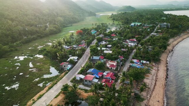 Panoramic aerial pullback of coastal village community with lush tropical island greenery - Igang, Virac, Catanduanes, Philippines