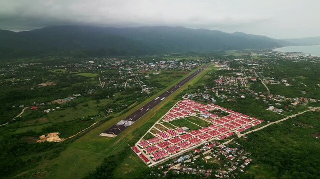 Aerial overview of Virac Airport in Catanduanes, Philippines, with a lone runway, residential homes, and tropical island greenery