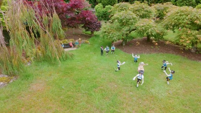 Miniature Morris dancers and musicians perform in Godshill model village, Isle of Wight. Camera pans left across a landscaped garden with tiny figures in traditional dress.