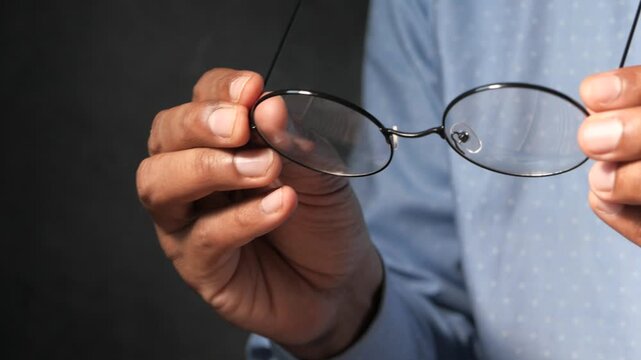 Close up of man holding scratched glasses lens for examination