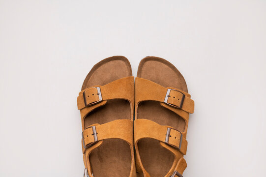Stylish summer sandals. Women's or men's open-toe shoes, top view copy space. Fashion, comfortable footwear, wardrobe essential. Brown leather sandals with cork soles.