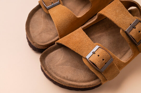 Close-up of brown leather summer sandals on beige background. Unisex open-toe shoes, stylish, fashionable sandals for everyday wear, leisure, and travel. Fashion, wardrobe essentials