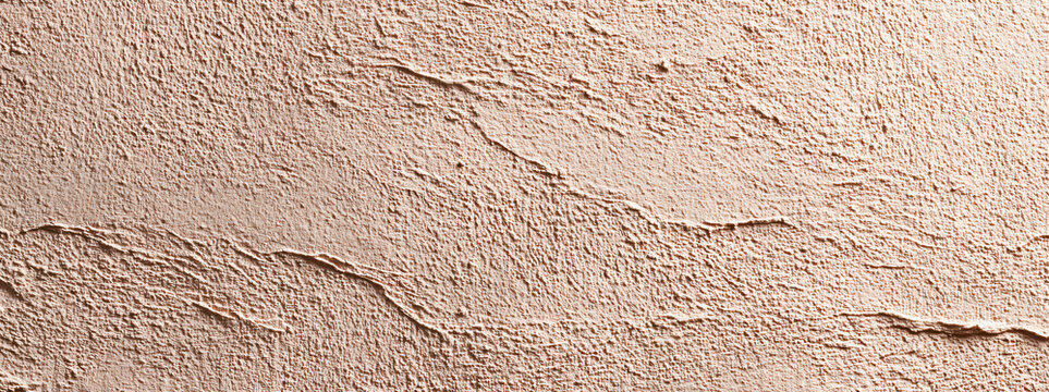 Pale peach clay plaster wall with layered hand-applied ridges and rough patches