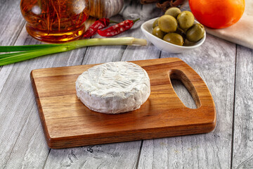 Fototapeta premium Round Camembert Cheese on Wooden Board with Olives and Spices