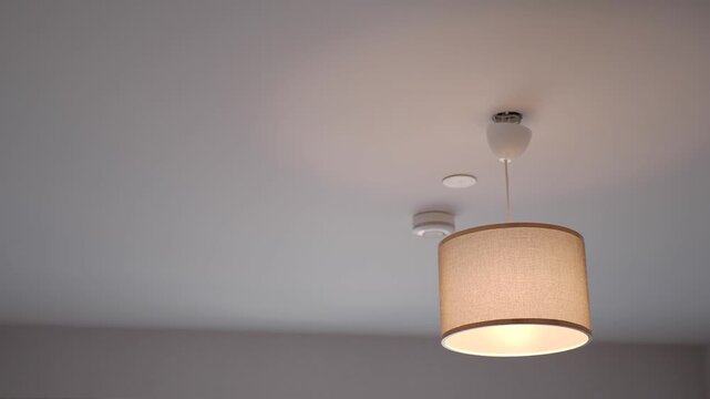 A motion footage showing a modern ceiling lamp with a brown fabric shade turning on and off in a contemporary room