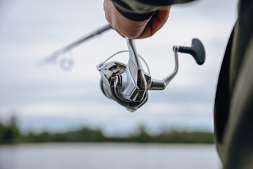 A spinning rod with a spinning reel in the hands of a fisherman © smiltena