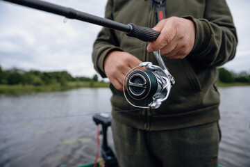 A spinning rod with a spinning reel in the hands of a fisherman © smiltena