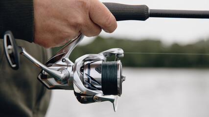 A spinning rod with a spinning reel in the hands of a fisherman © smiltena