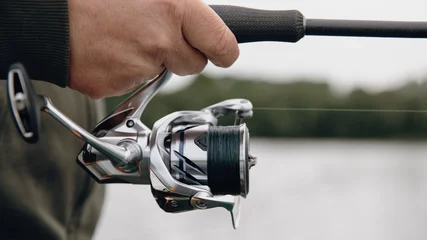 A spinning rod with a spinning reel in the hands of a fisherman © smiltena