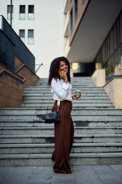 African American Businesswoman Talking on Phone With Coffee on Urban Stairs, Confident Professional