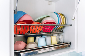 Organized colorful plates and cups in a modern kitchen dish rack