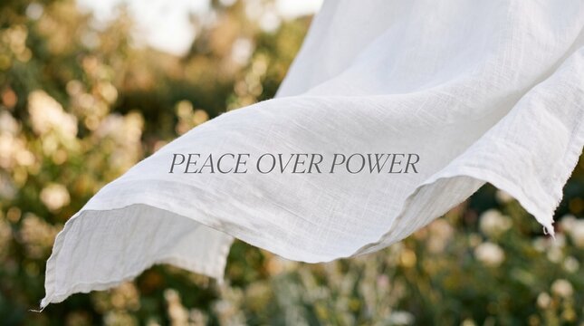 Peace over power text overlay on a flowing white linen fabric against a blurred natural garden background