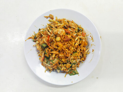 A plate of Karedok.  It is a raw vegetable salad from West Java, Indonesia includes long beans, cucumbers, bean sprouts, cabbage, lemon basil, small green eggplant, covered in peanut sauce dressing