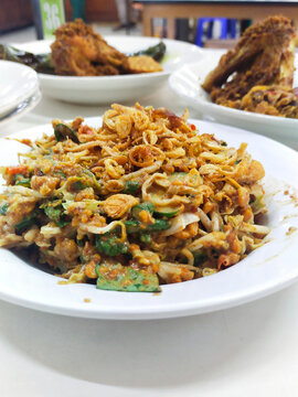 A plate of Karedok.  It is a raw vegetable salad from West Java, Indonesia includes long beans, cucumbers, bean sprouts, cabbage, lemon basil, small green eggplant, covered in peanut sauce dressing