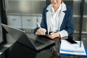 Fototapeta premium Stylish woman works in digital marketing, typing on laptop and smartphone at office desk. Social media, business.
